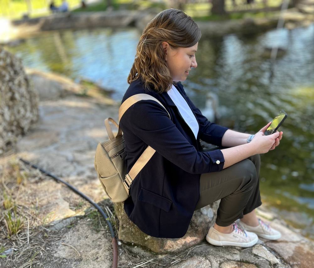 Dorota Anna junto al lago del parque, respondiendo desde el móvil